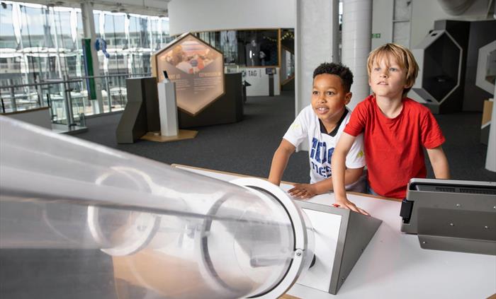Two boys play with the Rocket Launch exhibit that fires rockets up two tubes simultaneously.